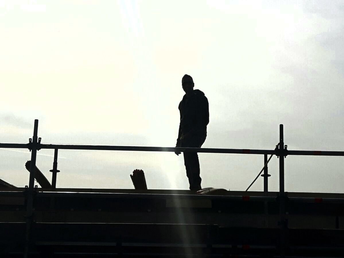 Monteur in silhouet aan het werk op een dak in het werkgebied
